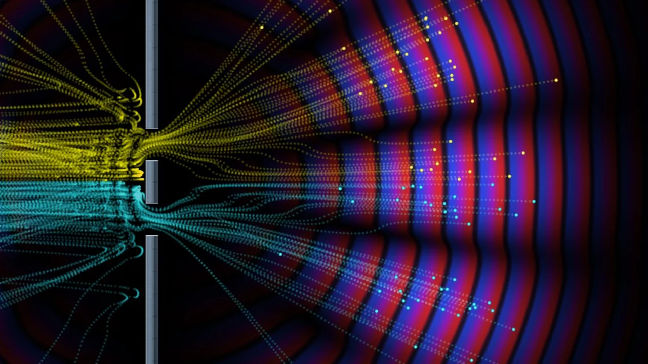 Red and blue waves interfere beyond two slits while yellow and cyan particle paths spread through the pattern.